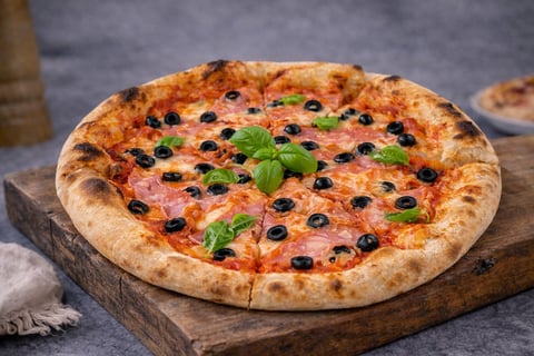 Margherita pizza with black olives and fresh basil on a wooden board