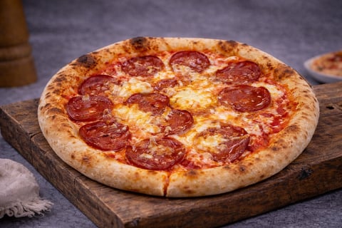Pepperoni pizza on wooden board with melted cheese and golden crust