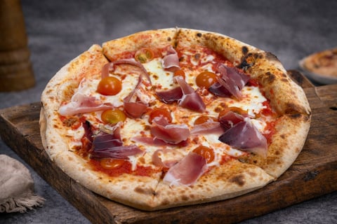 Neapolitan pizza with cured meats and cheese on wooden board