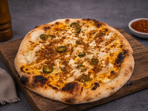 Freshly baked pizza with melted cheese and jalapeno slices on a wooden board